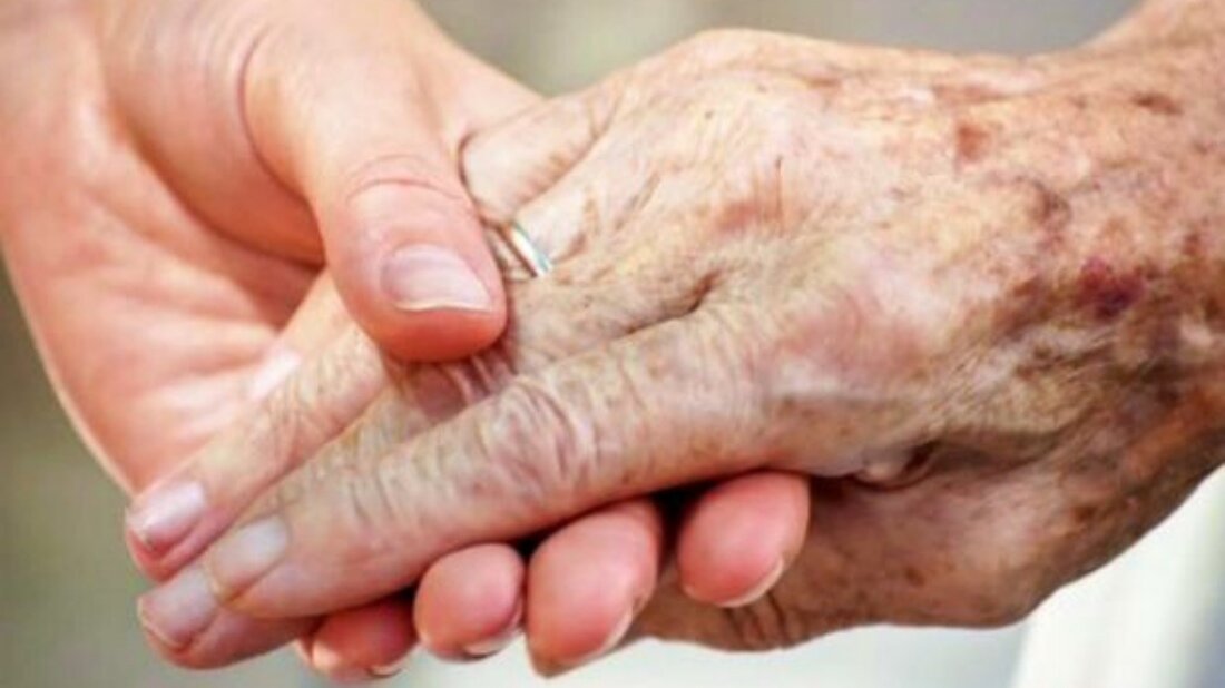 Una joven sujeta la mano de una persona mayor. Una joven sujeta la mano de una persona mayor.