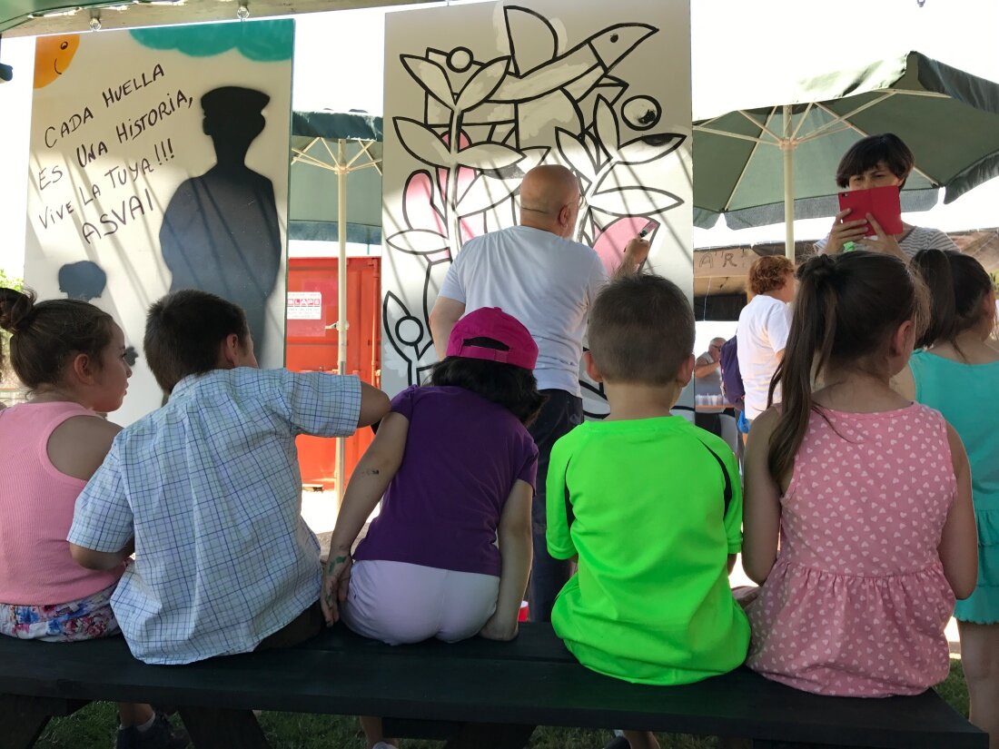 Manuel Sierra pinta su mural ante la atenta mirada de los niños que participaron en las actividades. Foto: úC